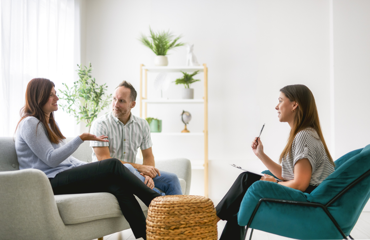 a couple sitting on a couch speaking with their couples counselor